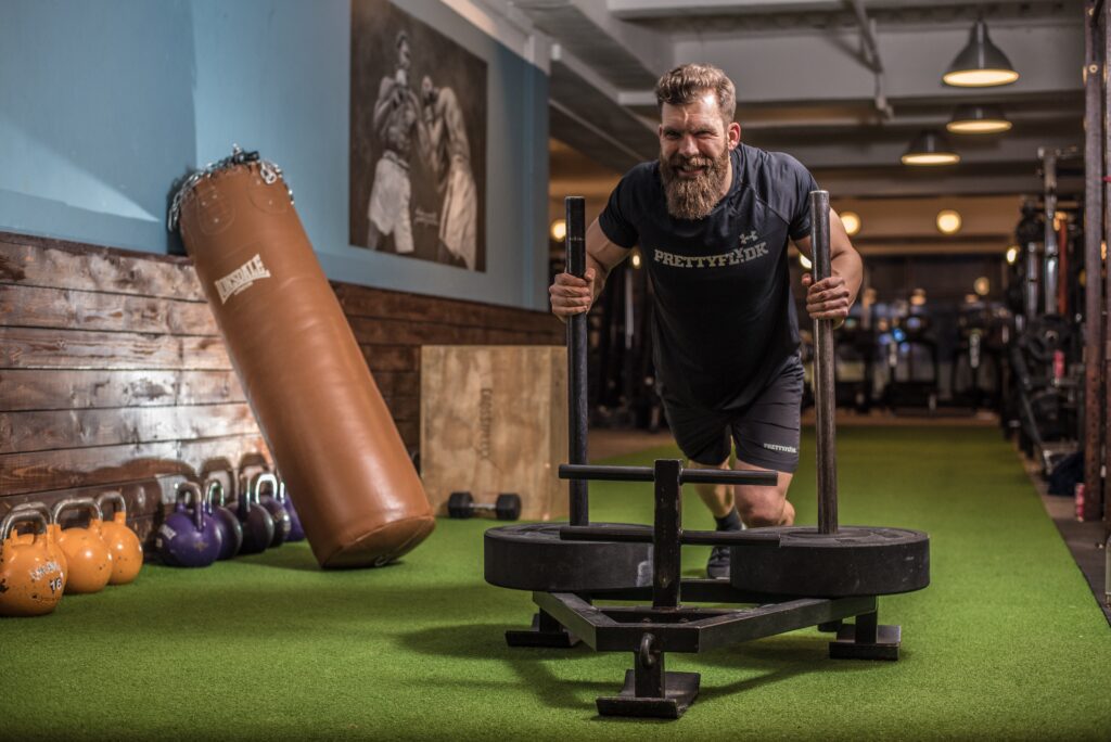 male crossfit athlete pushes sled